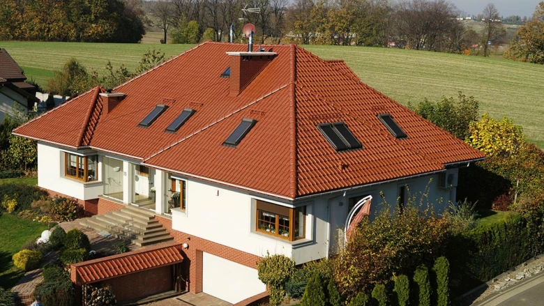 Moderní dům s červenou sedlovou střechou na venkově.