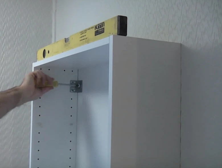 Zavěšení horní skřínky pomocí šroubováku a úrovně.