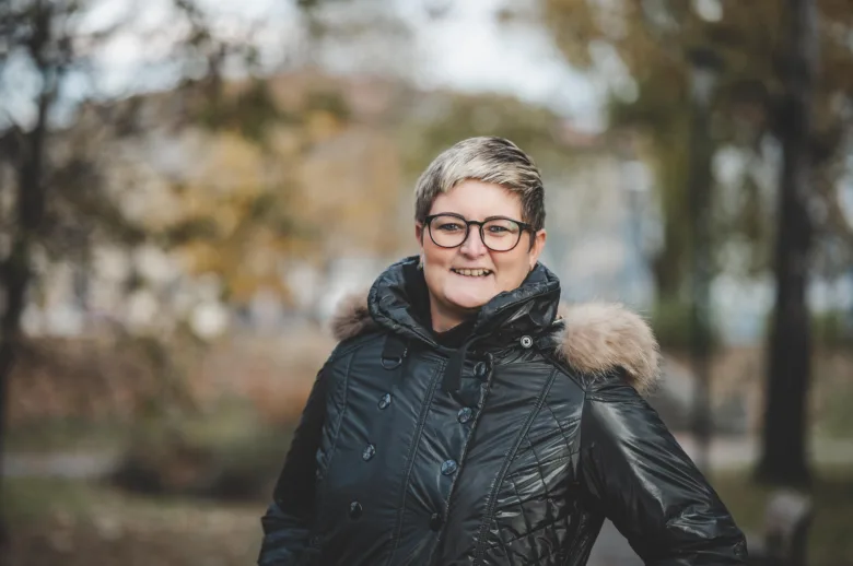 Žena v zimní bundě na pozadí podzimu, ne souvisí s přepisem energií.