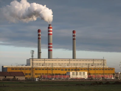 Velká elektrárna na uhlí s třemi komíny vypouštějícími páru.