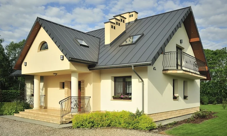 Modern dům s plechovou střechou na pozadí zelené zahrady.