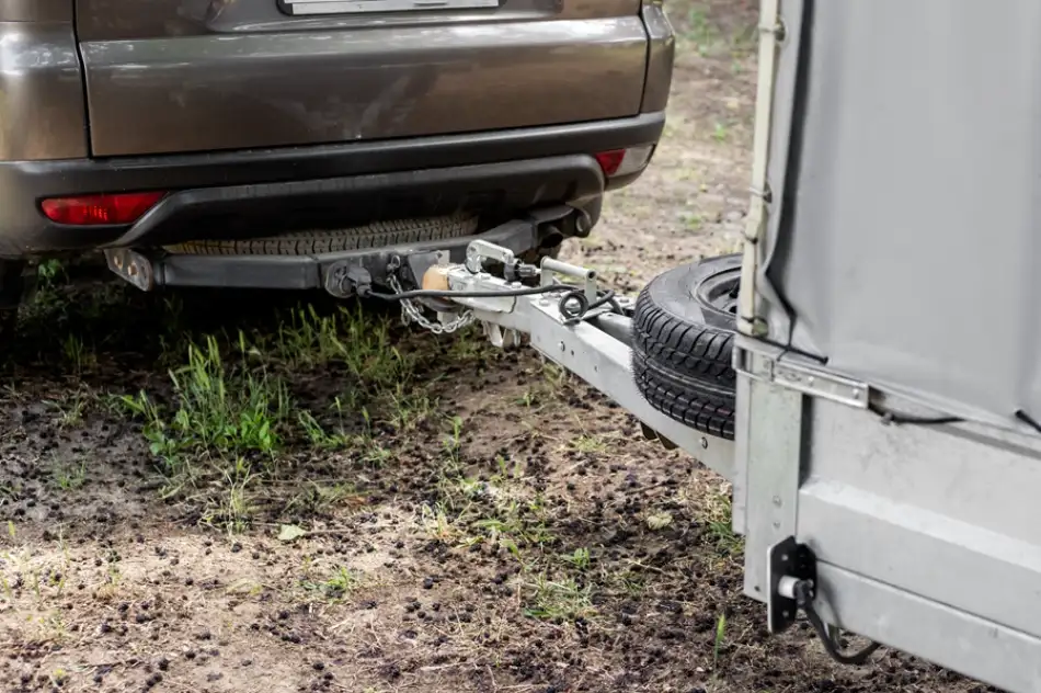 Přívěsný vozík připojený k automobilu pomocí tažného háku.
