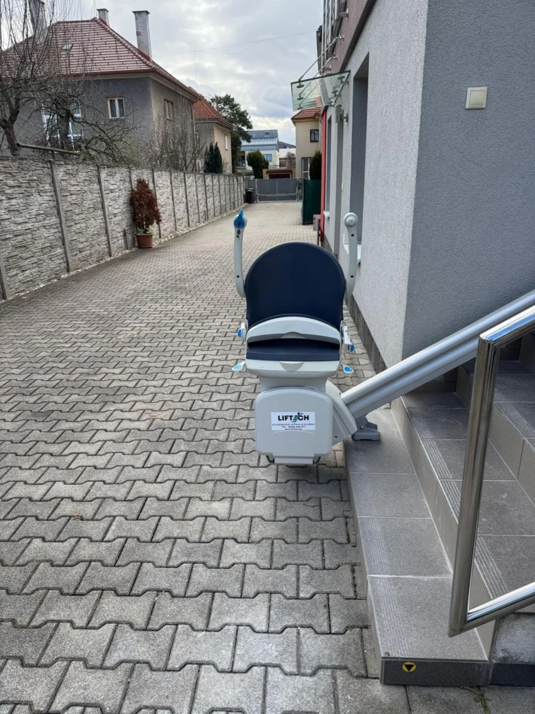 Venkovní schodišťový výtah vedle domu pro bezbariérový přístup.