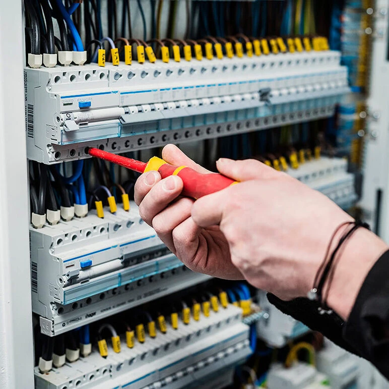 Technik opravuje průmyslové rozvaděč s kabely v českém podniku.
