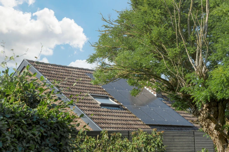 Fotovoltaické panely na střeše rodinného domu pod modrou oblohou.