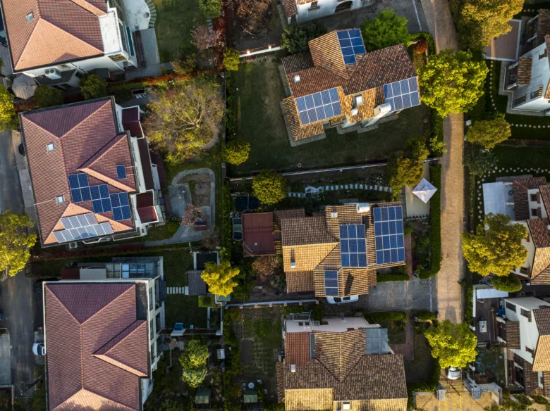 Vzdušný pohled na domy s fotovoltaickými panely na střechách.