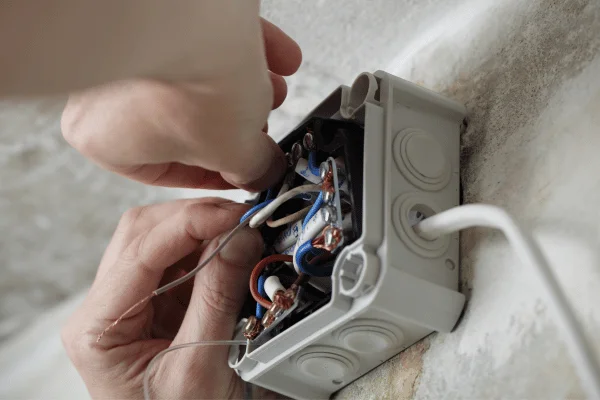 Ruční instalace elektrického vedení v domácnosti s odpojenými vodiči.