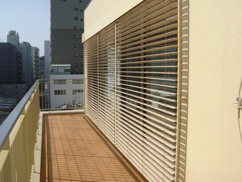 Venkovní žaluzie na balkóně s výhledem do města.