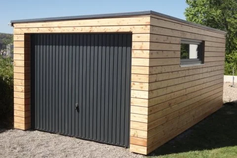 Moderní garáž z dřeva s ocelovou vratem na kamenné podlaze.