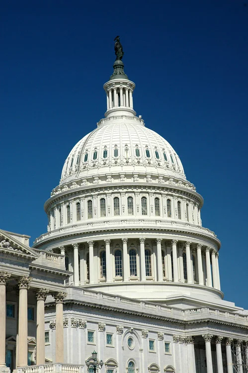 Bílá kopule Kapitolu v Washingtonu s sochou na vrchole.