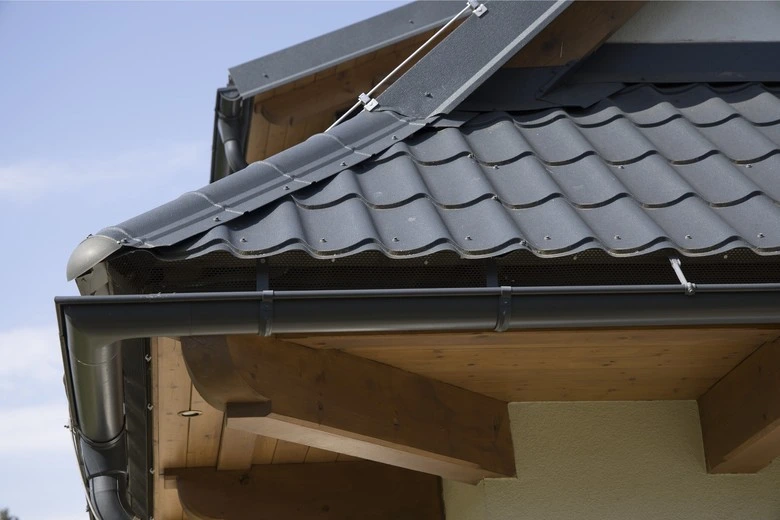 Detailní pohled na montáž plechové střechy s okapem.