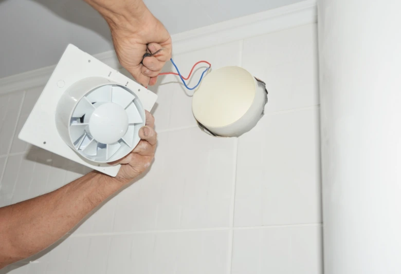 Instalace ventilátoru do dlažby v koupelně s připojením kabelů.