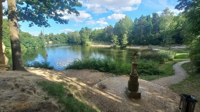 Přírodní koupání v Plzni u klidného jezera s okolní zeleň.