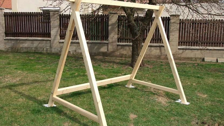 Dřevěná konstrukce houpačky na zahradu postavená z prken.