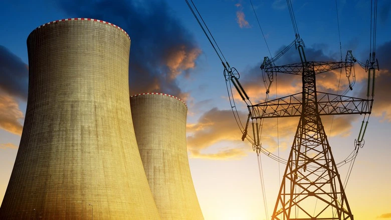 Dva chladiče jaderné elektrárny s vysokonapěťovými vedeními na pozadí západu slunce.
