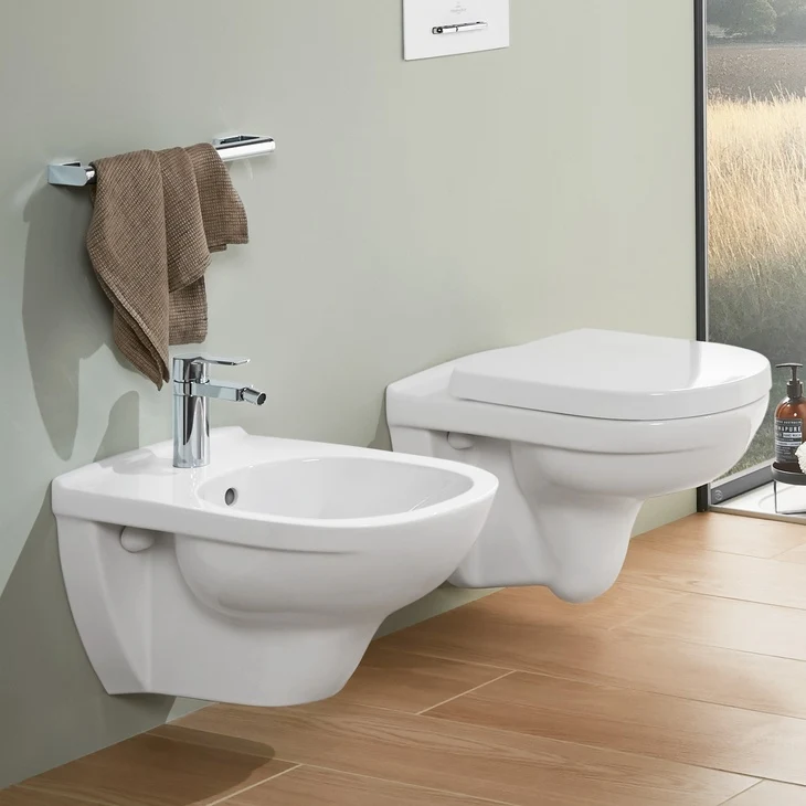 Zdi montovaný bidet vedle zdi montované toalety v koupelně.