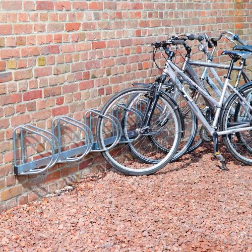 Stojan na kola s několika bicykly u zdi.