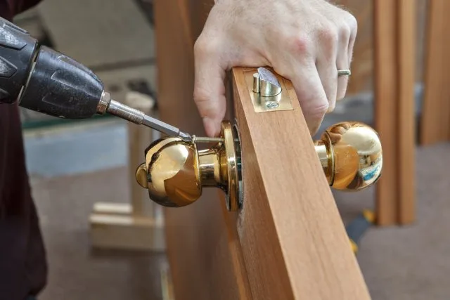 Montáž zámku dveří pomocí vrtáku při renovaci.