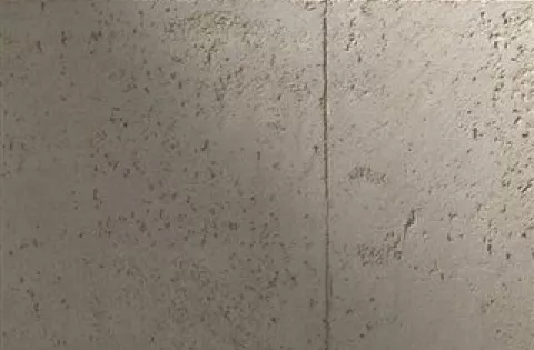 Detail pohledového betonu na exteriérovém plotu s viditelnou texturou.