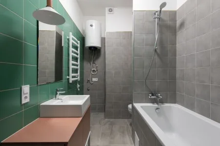 Moderní koupelna s vanou, sprchovým koutem a zelenými obklady.
