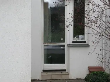 Skleněná výplň do bílých dveří na fasádě domu.