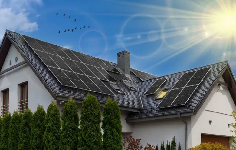 Moderná rodinný dům s fotovoltaickými panely na střeše pod sluncem.