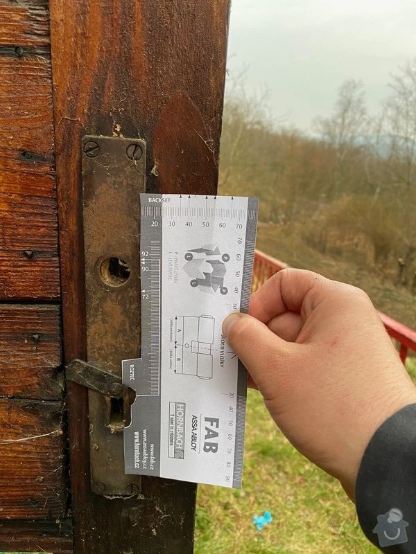 Měřicí nástroj pro instalaci zámku na dřevěných dveřích v Praze.