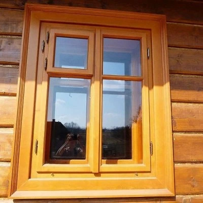 Dřevěné okno v dřevěném domě na pozadí zeď z kmenů.