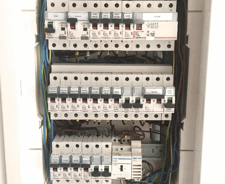 Vnitřek stavebního rozvaděče s pojistkami a vodiči v domovní elektroinstalaci.
