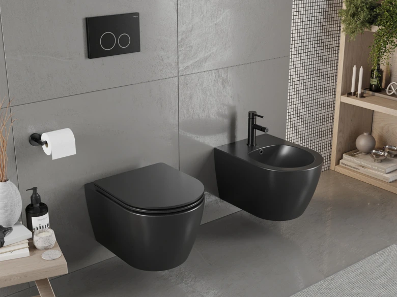 Černý bidet nainstalovaný vedle zdi s WC v šedé koupelně.