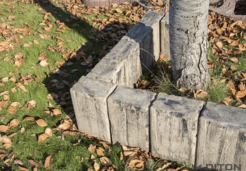 Betonové obrubníky kolem stromu na trávníku s listím.