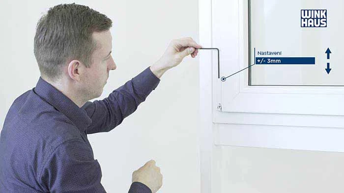 Muž nastavuje plastové okno pomocí nástroje pro přesné seřízení rámu