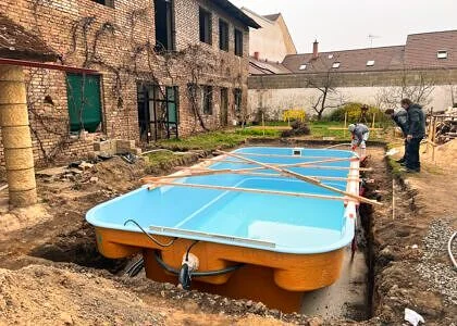 Modrý bazén se instaluje do příkopu vedle domu.