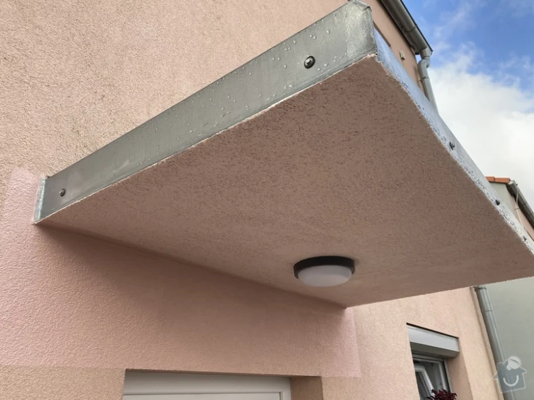 Nová betonová předsíňka nad dveřmi po montáži na fasádě domu.