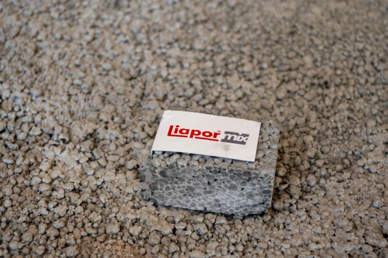 Malý kus lehčeného betonu s logem Liapor mix na zrnitém podkladu.