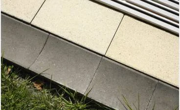 Detailní pohled na dlažbu terasy s trávníkem u okraje.