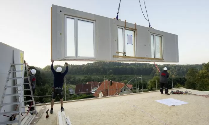 Montáž prefabrikovaného střevního panelu na stavbě s dělníky.
