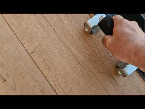 Pracovník používá elektrický stroj na úpravu podlahy v starém domě.