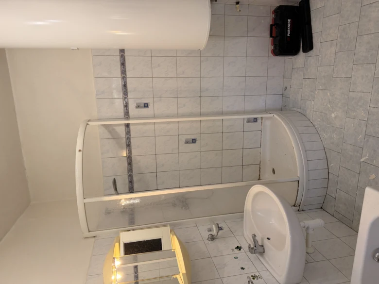 Koupelna v průběhu renovace bez bourání s odmontovaným umyvadlem a vanou.