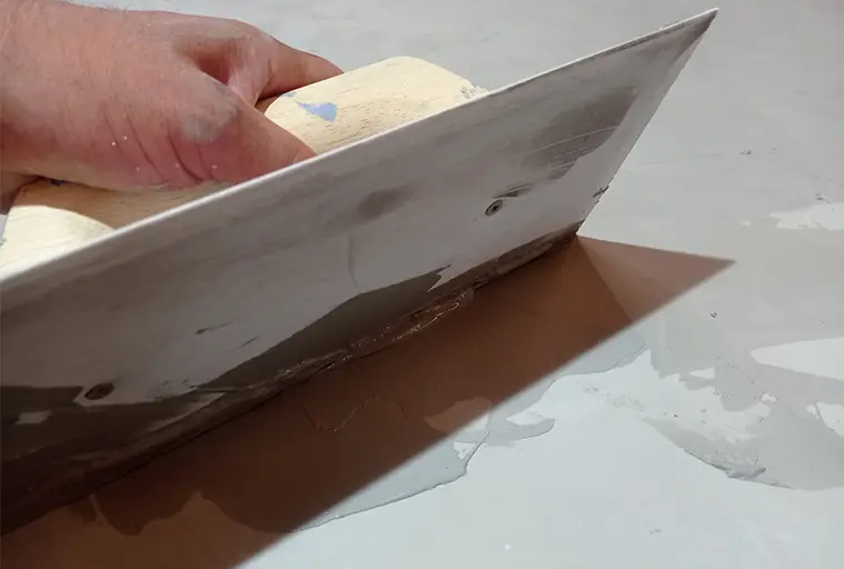 Ruční rozšiřování šedého mikrocementu stěrka na povrch.