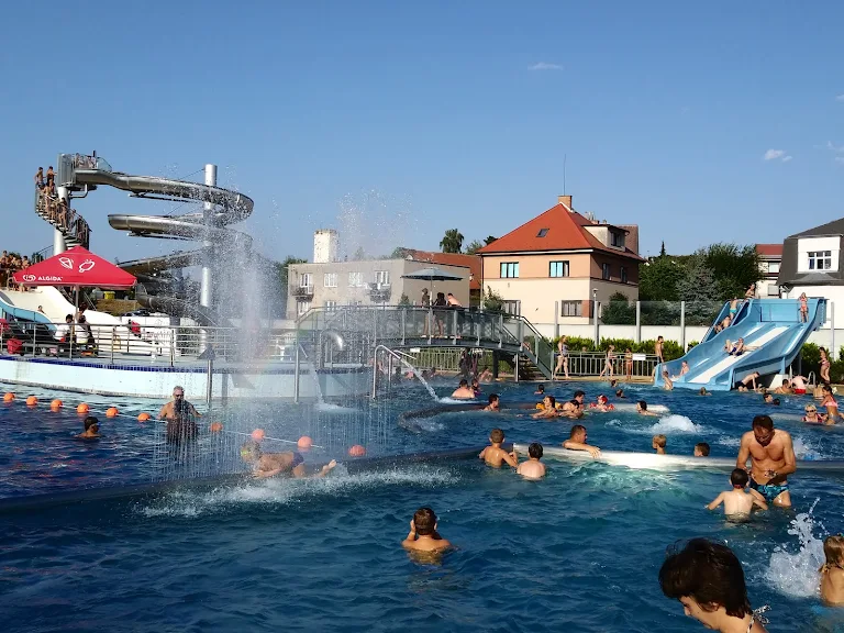Lidé plavou v bazénu s vodními skluzavkami