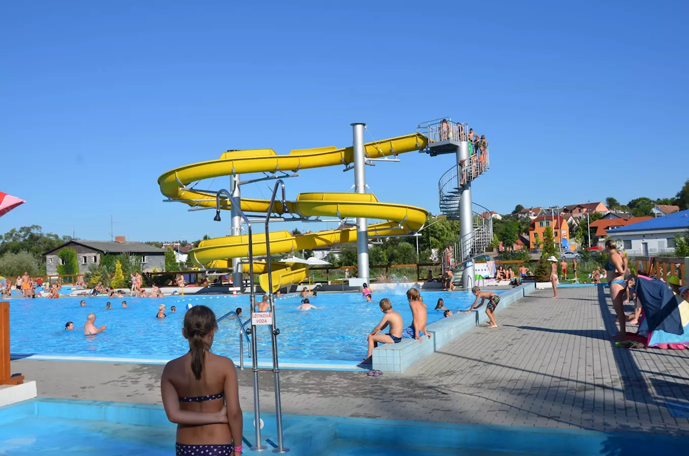 Venkovní bazén ve Vlašimi s žlutými vodními skluzavkami.