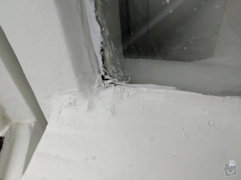 Detailní pohled na aplikaci těsnící hmoty v rohu rámu dveří s výplní.