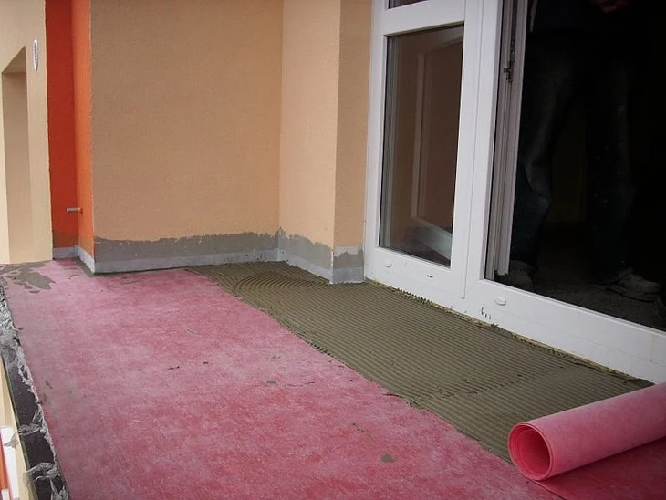 Balkon v rekonstrukci s rolovanou izolační fólií a lepidlem.
