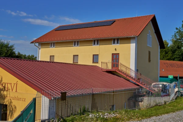 Žlutý dům s fotovoltaickými panely a zateplením pro dotace.