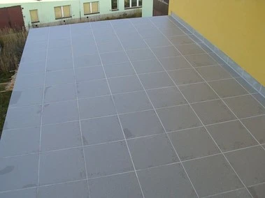 Nově dlažděná šedá podlaha na balkónu po rekonstrukci.