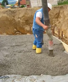 Stavebník nalévá beton z hadice do výkopu.