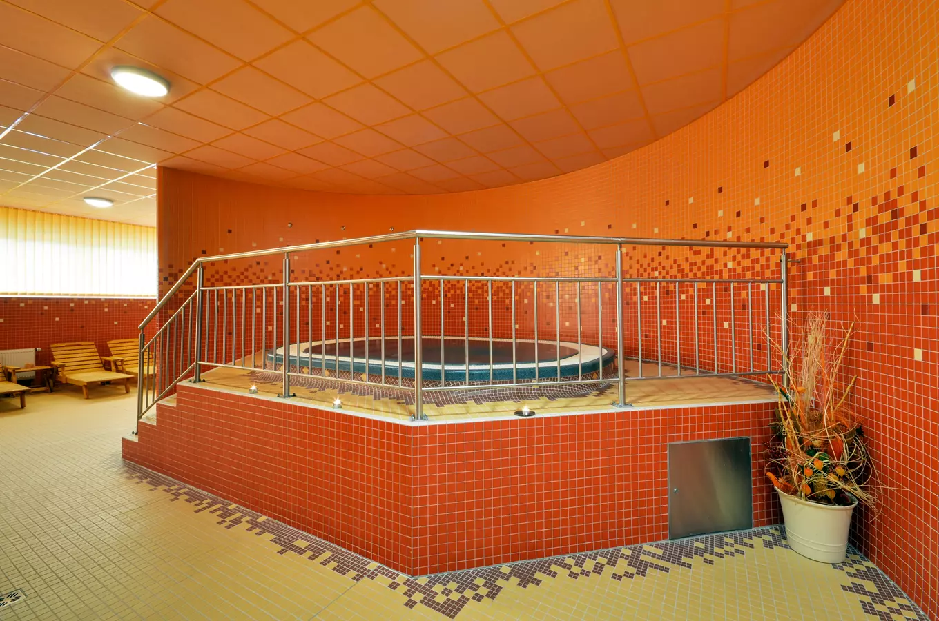 Vnitřní sauna s horkou vanou v oranžových dlaždicích.