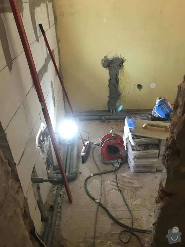 Koupelna v rekonstrukci s viditelnými instalacemi a stavebními materiály.