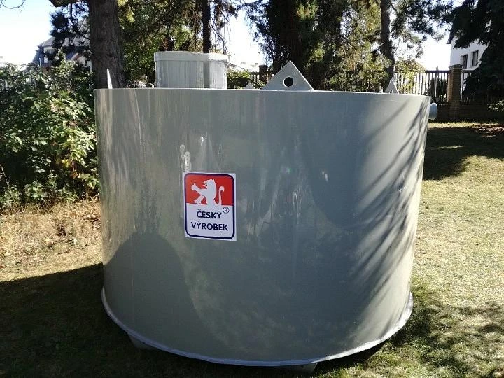 Šedý septik na trávníku v zahradním prostředí.